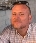 A person with sunglasses on his headDescription automatically generated with medium confidence