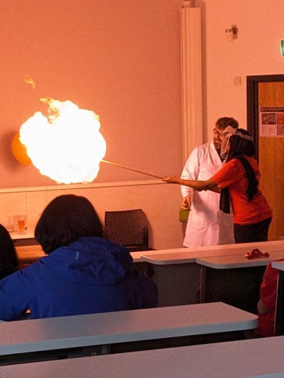 A person holding a stick with a flame in front of a personDescription automatically generated