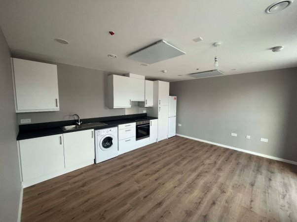 A kitchen with white cabinets and a wood floorDescription automatically generated