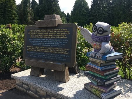 A statue of an owl pointing at a signDescription automatically generated