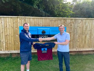 Two men standing in front of a T H Wood sign