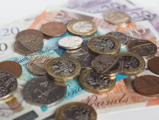 A selection of UK currency including £1 coins, £5 and £10 notes.