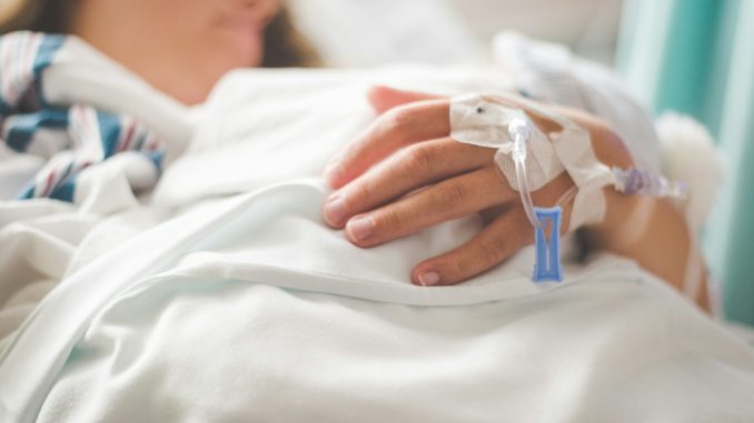 a woman laying in a hospital bed with an iv in her hand