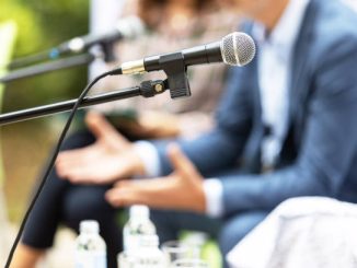 Microphone in focus against blurred people at round table event or business conference