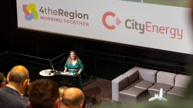 A woman speaking to an audience at a lectern.