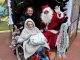 A young patient in a wheelchair sitting in Santa's grotto with Santa.