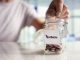 A person putting money into a glass jar labelled "pension".