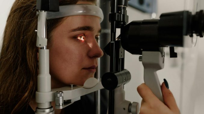 A woman undergoing an eye examination using a slit lamp in a modern clinic setting.