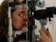 A woman undergoing an eye examination using a slit lamp in a modern clinic setting.