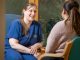 A City Hospice member wearing a blue uniform talking to a patient.