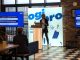 A person presenting at an event with the Ogi Pro logo in the background.