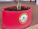 One of the bee friendly plant pots outside The Red Dragon Centre. A red plant pot with text reading: Achub Peillwr / Saving Pollinators.