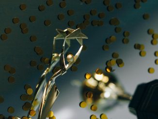 A gold trophy against a dark background surrounded by gold confetti.