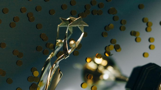 A gold trophy against a dark background surrounded by gold confetti.