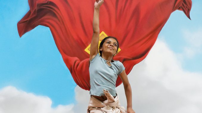 A child jumping in a Superman pose in front of the mural in The Red Dragon Centre