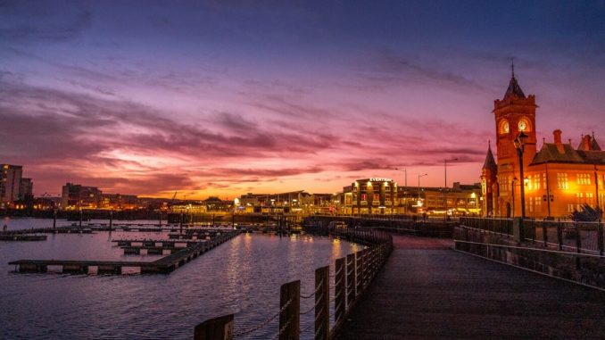 body of water near city buildings during sunset