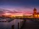 body of water near city buildings during sunset