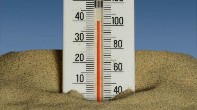 A thermometer in the sand with a blue sky in the background