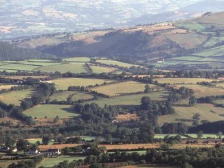 an aerial view of a valley with rolling hills in the background
