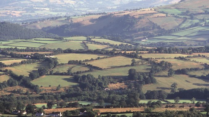 an aerial view of a valley with rolling hills in the background