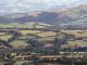 an aerial view of a valley with rolling hills in the background